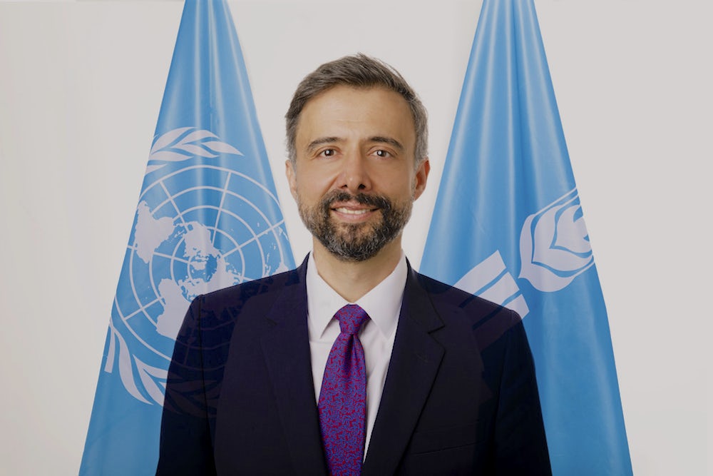 A portrait of Alvaro Lario, president of the International Fund for Agricultural Development (IFAD), with the UN and IFAD flags in the background.